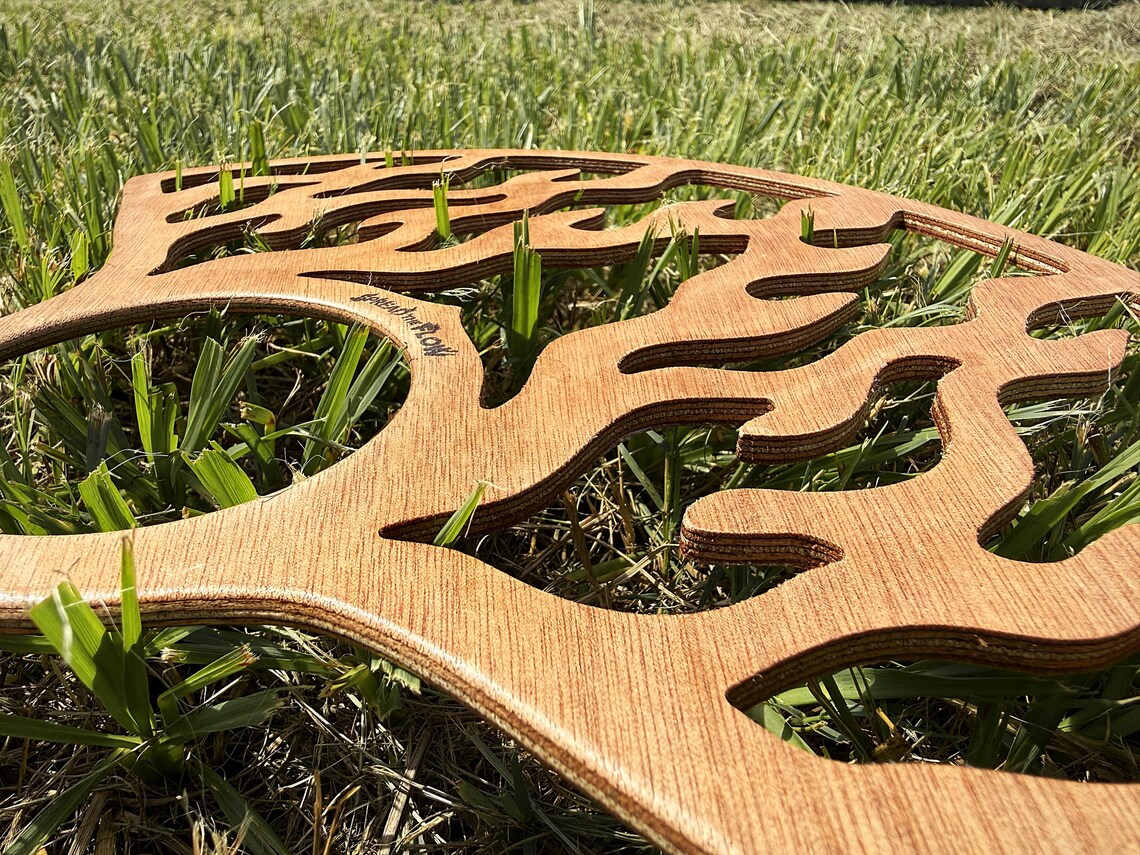 Close-up of the okoume grain and the cut flame edges, with the Spread The Flow mark engraved into the face