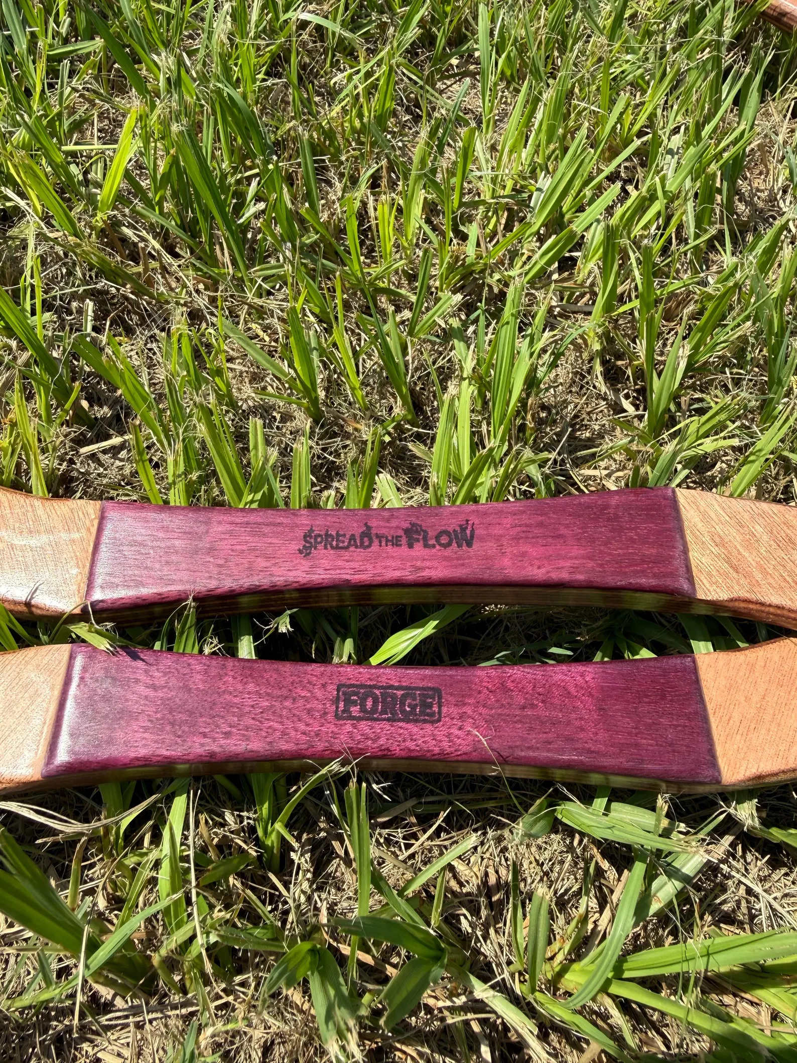 Close-up of the two Purpleheart center grips, one engraved with the Spread the Flow logo and the other with FORGE